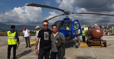 trekkers posing on heliport in front of blue helicopter