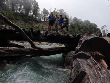 hikers posing atop a rustic wooden log bridge