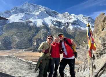 posing by prayer flags with mountains behind