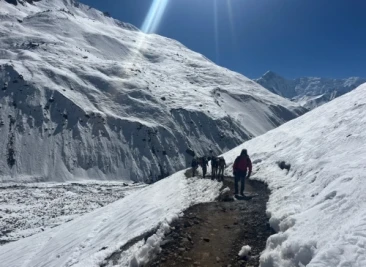 Trekkers walking narrow snowy trail